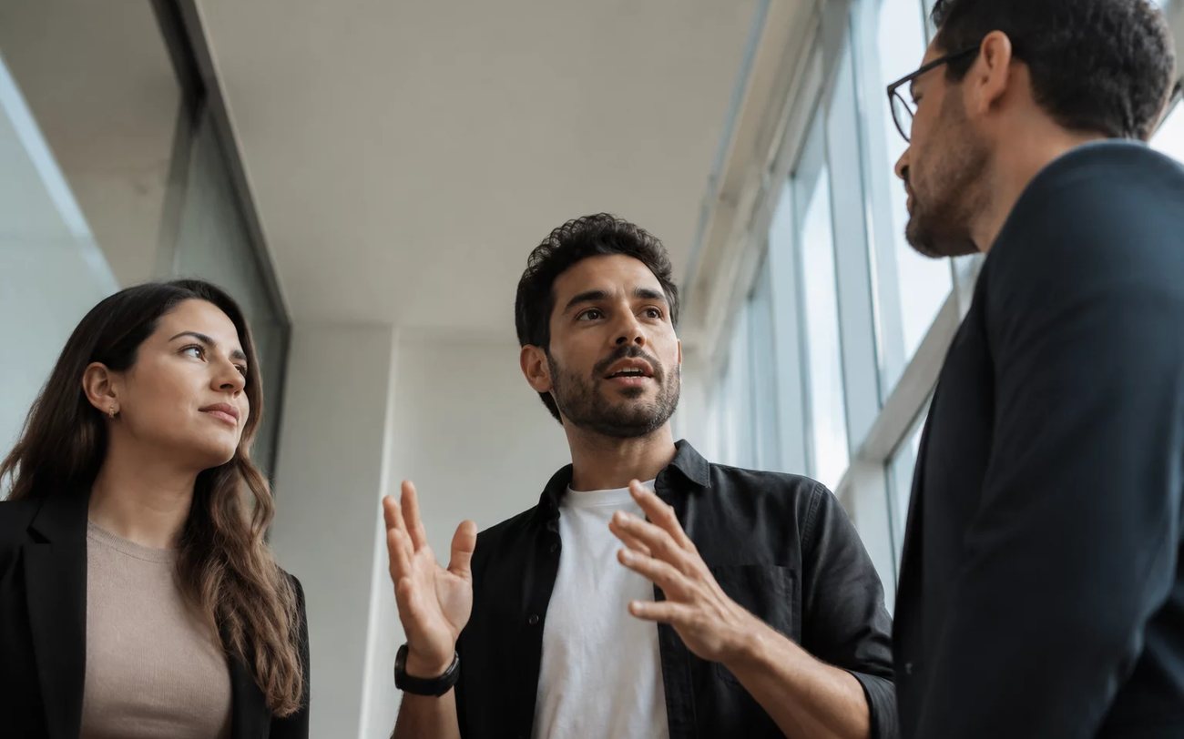 Roda de conversa numa sala clara, com uma pessoa expondo o ponto e duas escutando